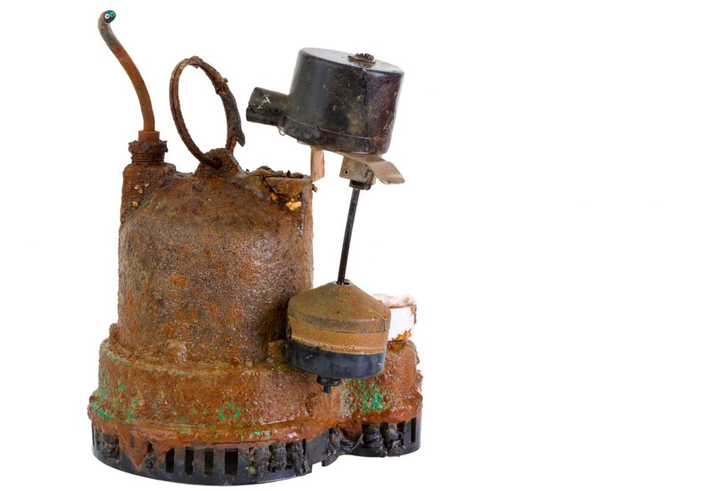 Old defunct obsolete grungy rusted sump pump that has been removed for replacement due to malfunction or breakdown, on white